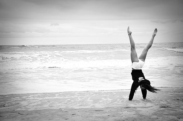 Frau macht Handstand am Strand